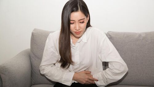 asian women in white sitting holding belly