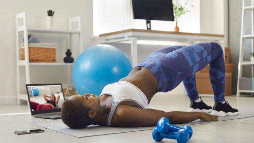 african american women doing bridge w hand weights and yoga ball