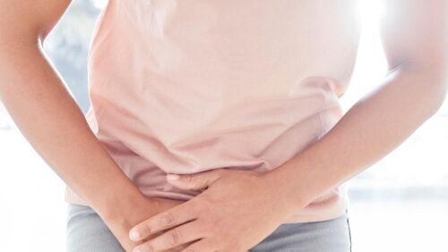 mid part of women in pink shirt grasping pelvis