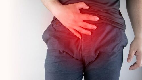 pelvis of man in grey red over pelvis holding pelvis