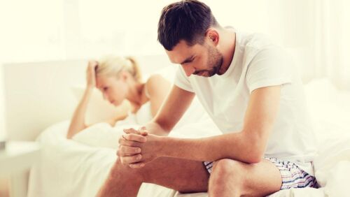 man edge of bed women behind both unhappy