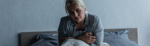 Woman sitting in bed in pain